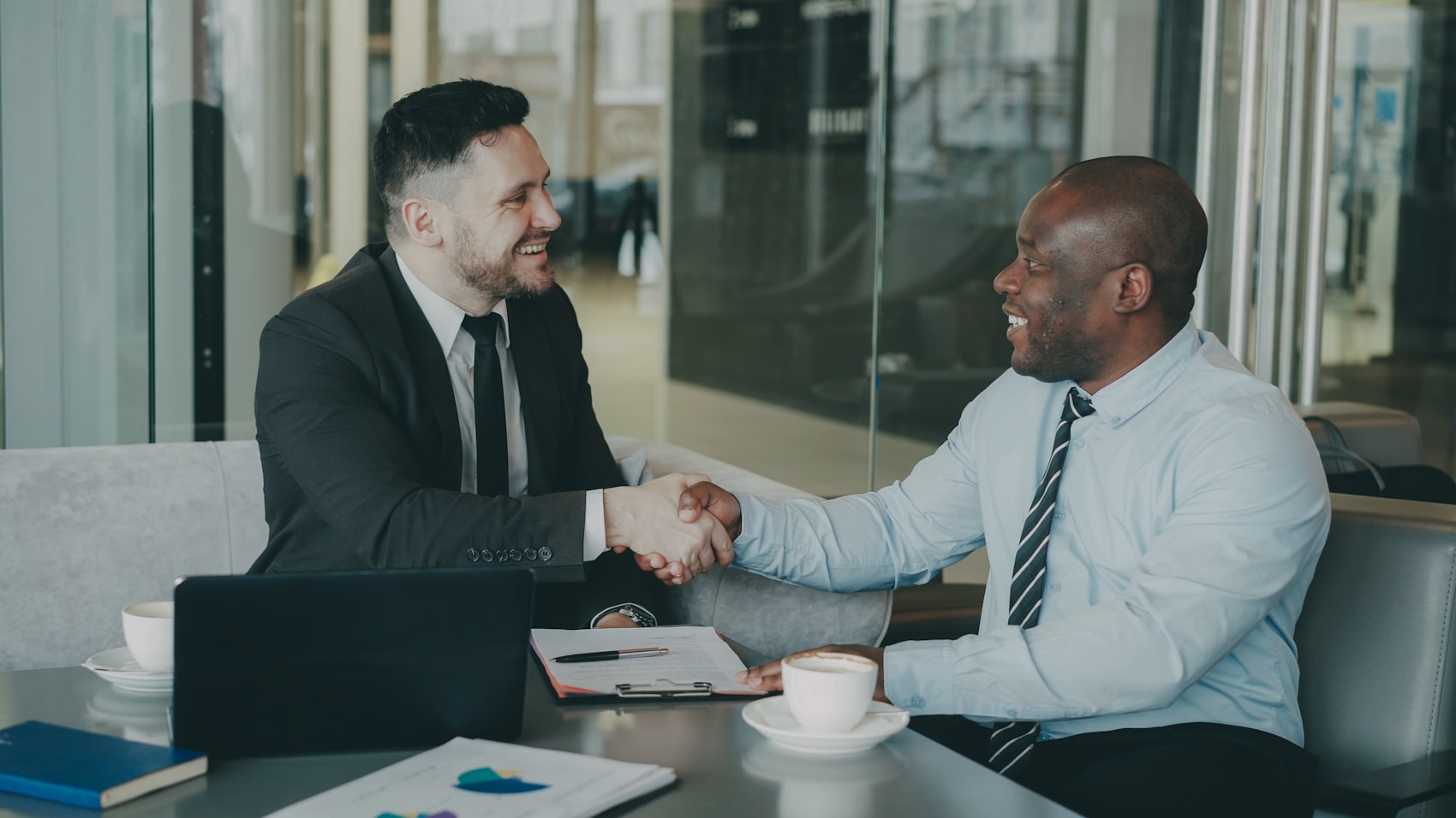 Two business partners shaking hands across a table